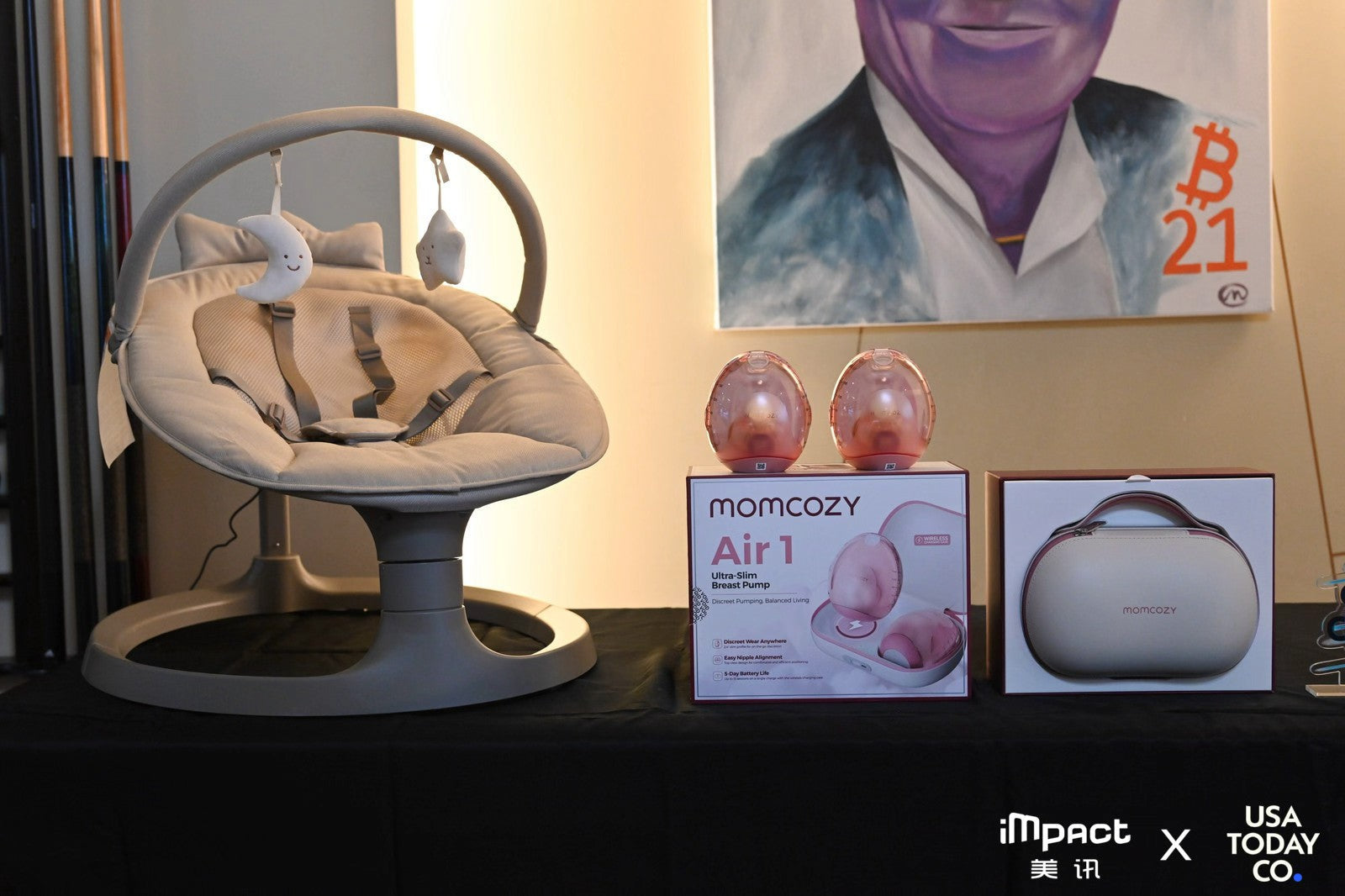 Momcozy 2-in-1 Electric Baby Swing and Air 1 Ultra-Slim Breast Pump display at CES 2026 with Impact x USA TODAY branding