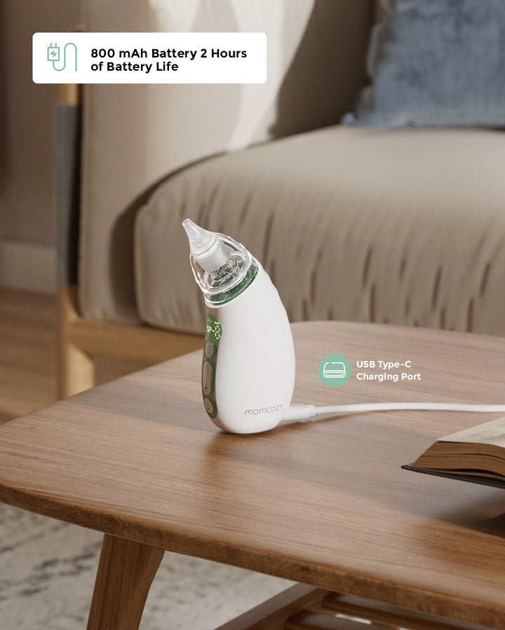 Momcozy Baby Nasal Aspirator with USB Type-C port and 800 mAh battery on a wooden table.