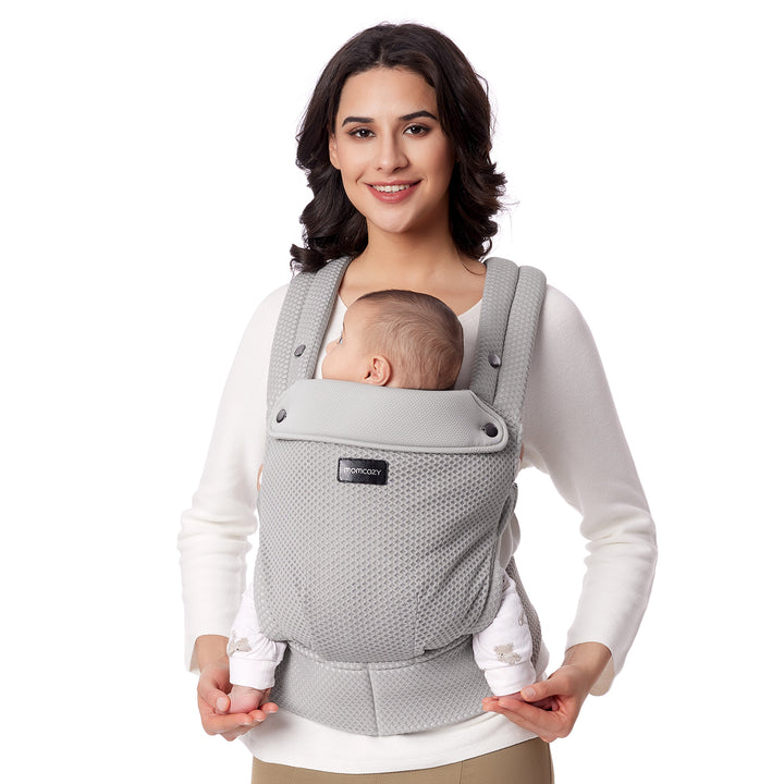 Woman holding baby in light gray Momcozy ergonomic carrier, promoting comfort and convenience.