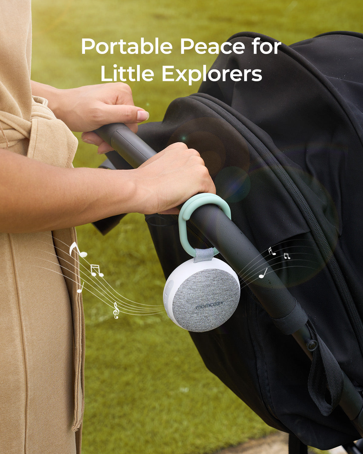 Momcozy portable sound machine attached to stroller, providing peace with white and gray speaker and green handle.