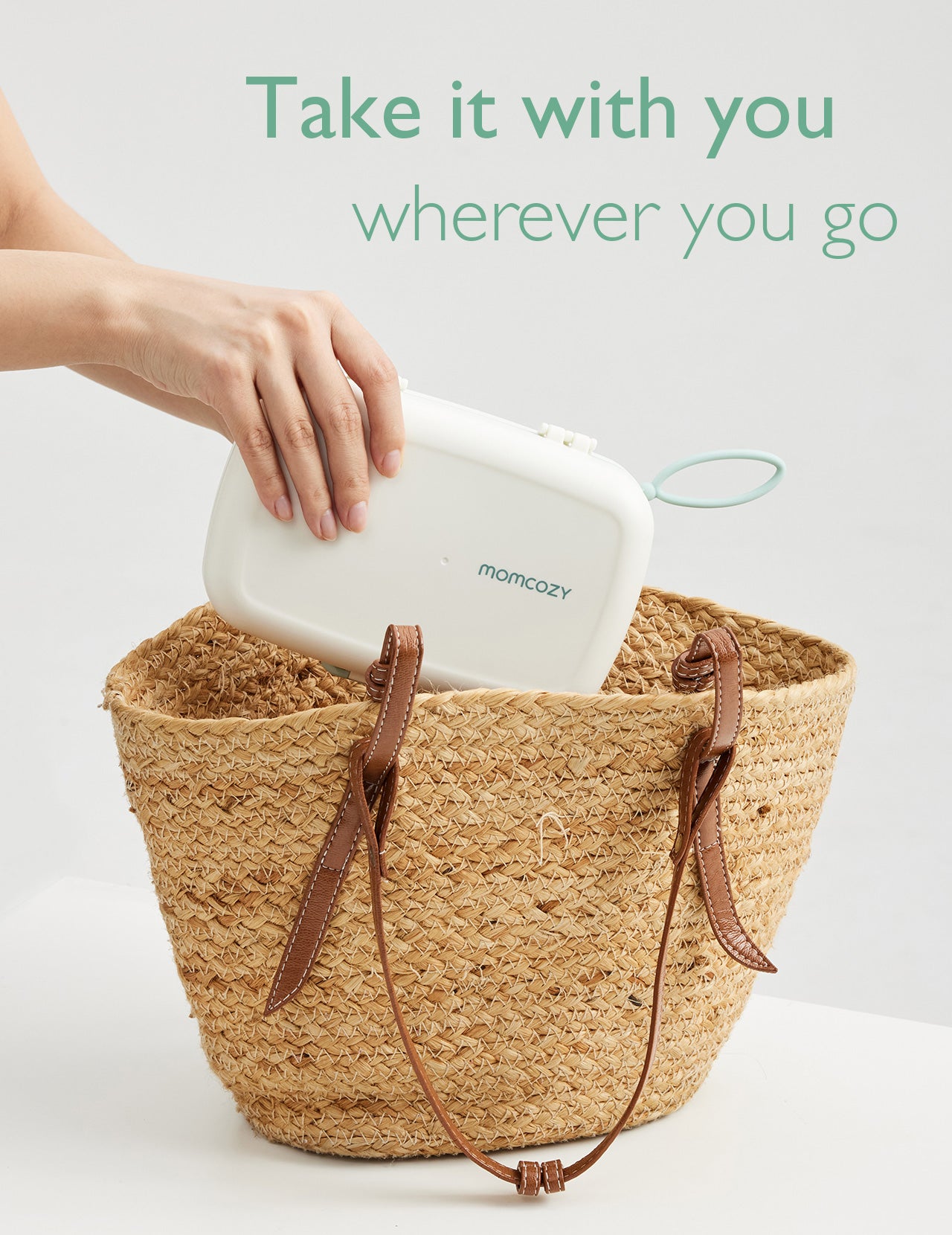 Momcozy portable bottle brush kit being placed in a woven tote bag, perfect for on-the-go use.