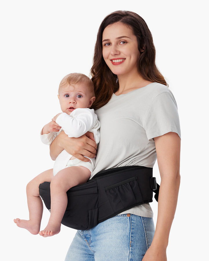 Woman holding a baby using a Momcozy Baby Hip Seat Carrier, showcasing a comfortable and convenient way to carry infants hands-free.