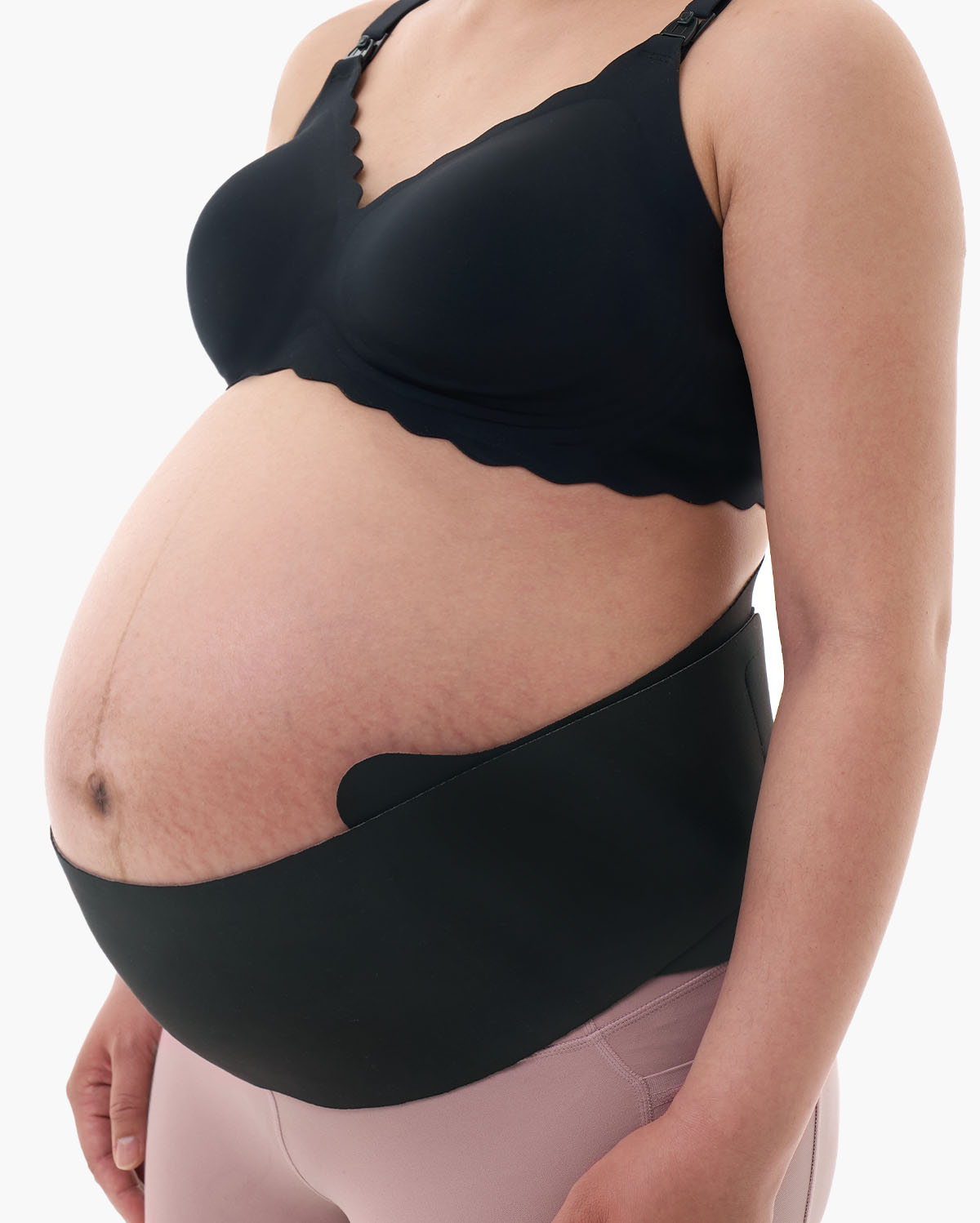 Black Momcozy Maternova belly band on a pregnant model wearing a pink leggings and black bra.