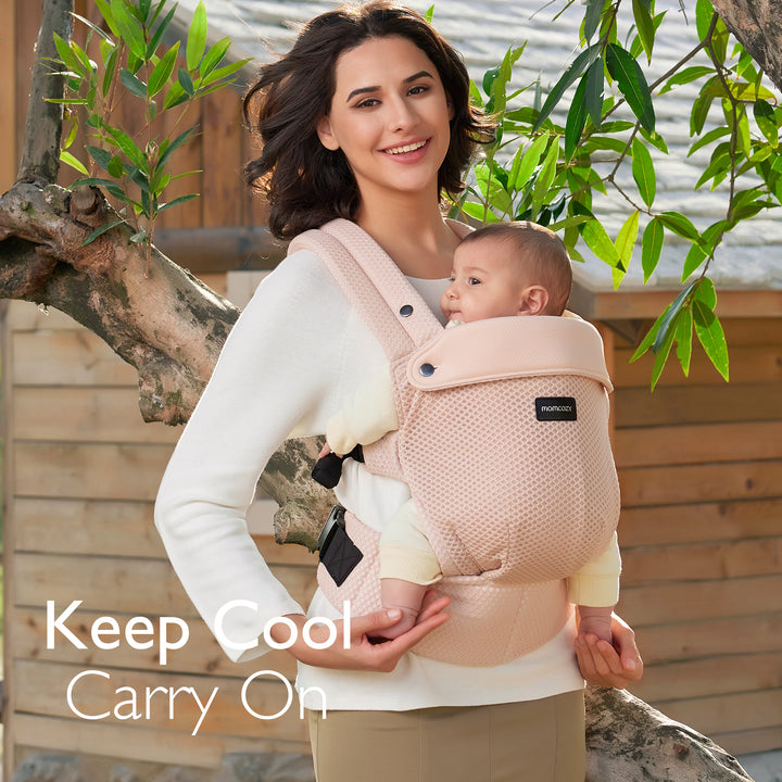 Momcozy air mesh-pink ergonomic baby carrier with a smiling infant, promoting comfort and hands-free convenience.