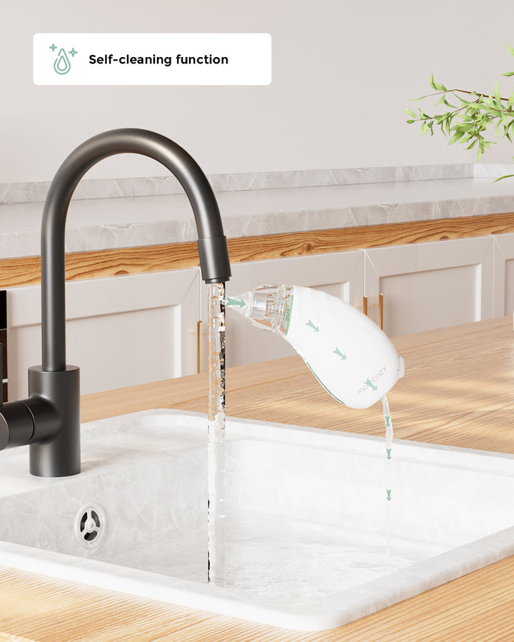 Momcozy Baby Nasal Aspirator showcasing self-cleaning function under kitchen faucet.