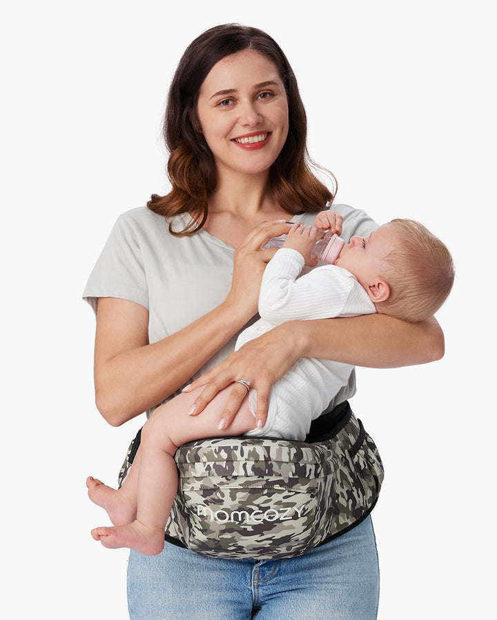 Mother holding her baby using the Momcozy baby hip seat carrier with camouflage pattern, perfect for comfort and support while nursing.