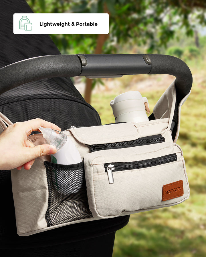 Momcozy stroller organizer bag with pockets for bottles and essentials in outdoor setting.