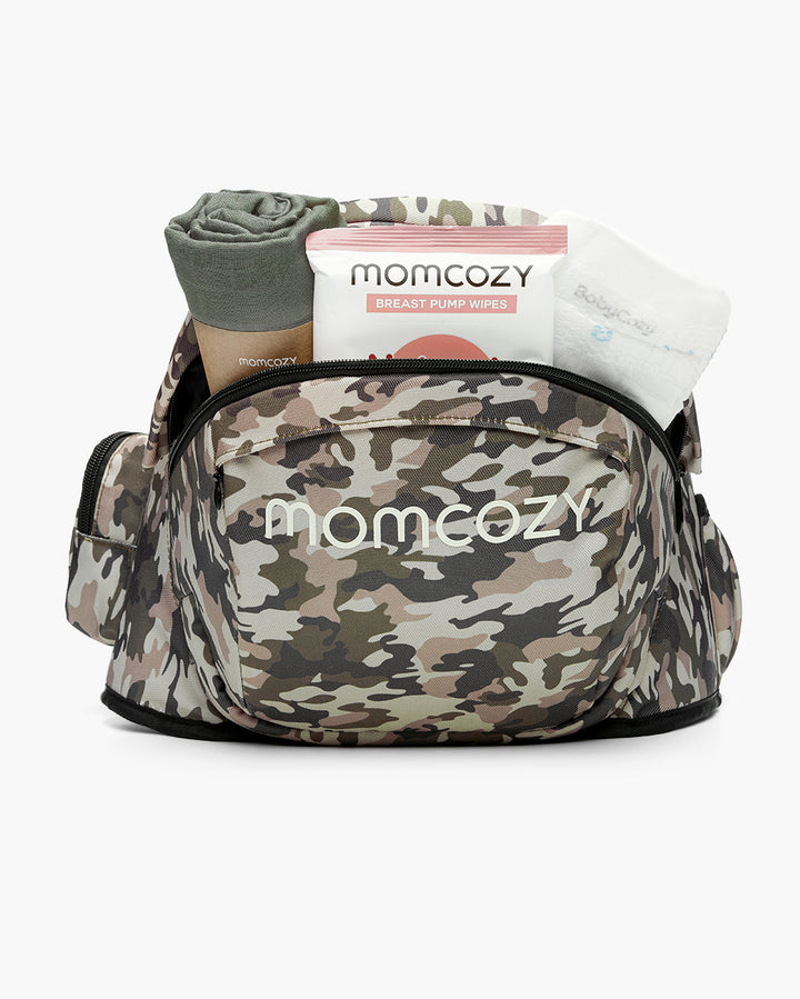 Camouflage Momcozy diaper bag filled with breast pump wipes, a green blanket, and baby wipes, showcasing the bag's large capacity and organization features.